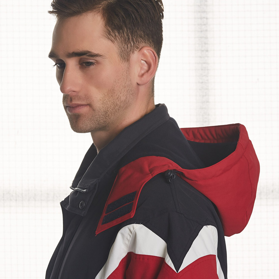 Male model wearing navy, red and white colour-block hooded racing jacket with snap collar detail