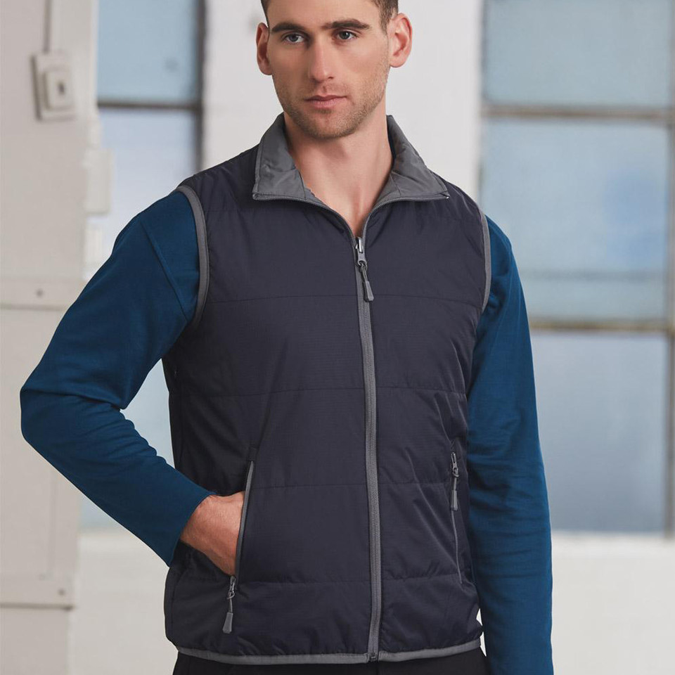 Man wearing a navy quilted reversible vest with grey contrast collar, full-length zip and side zip pockets