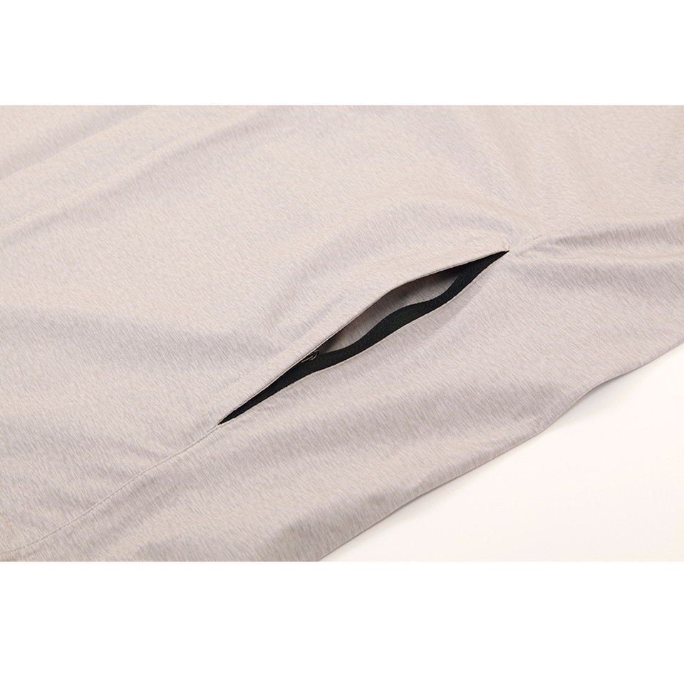 Close-up of light grey jacket side seam pocket with black zip pull on textured performance fabric