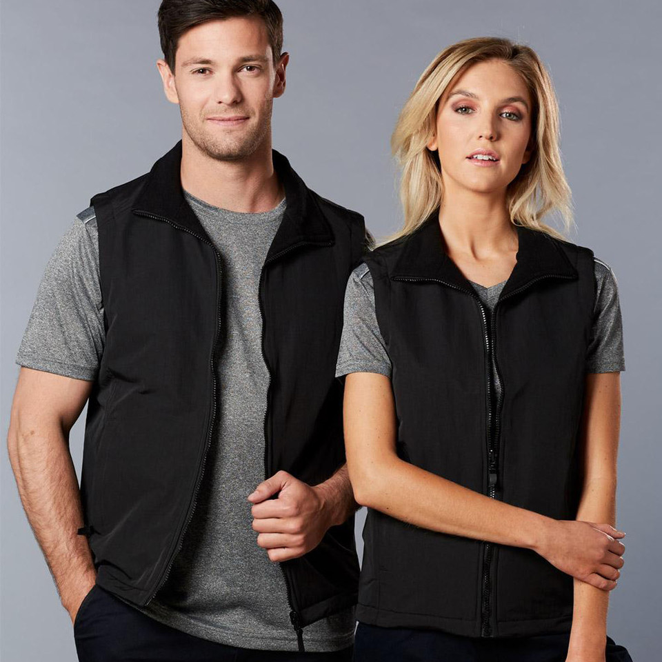 Male and female models wearing black reversible sleeveless vests with zip front and stand collar, styled over grey tees