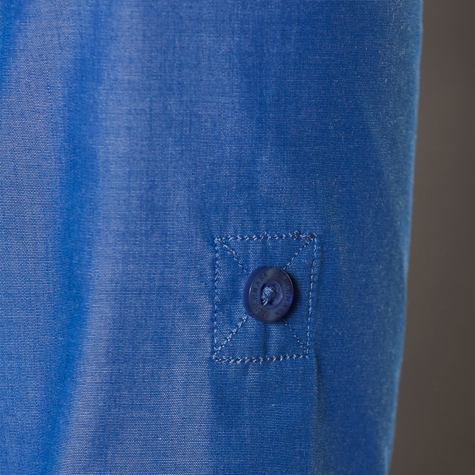 Royal blue dress shirt sleeve with visible button detail and matching stitched placket