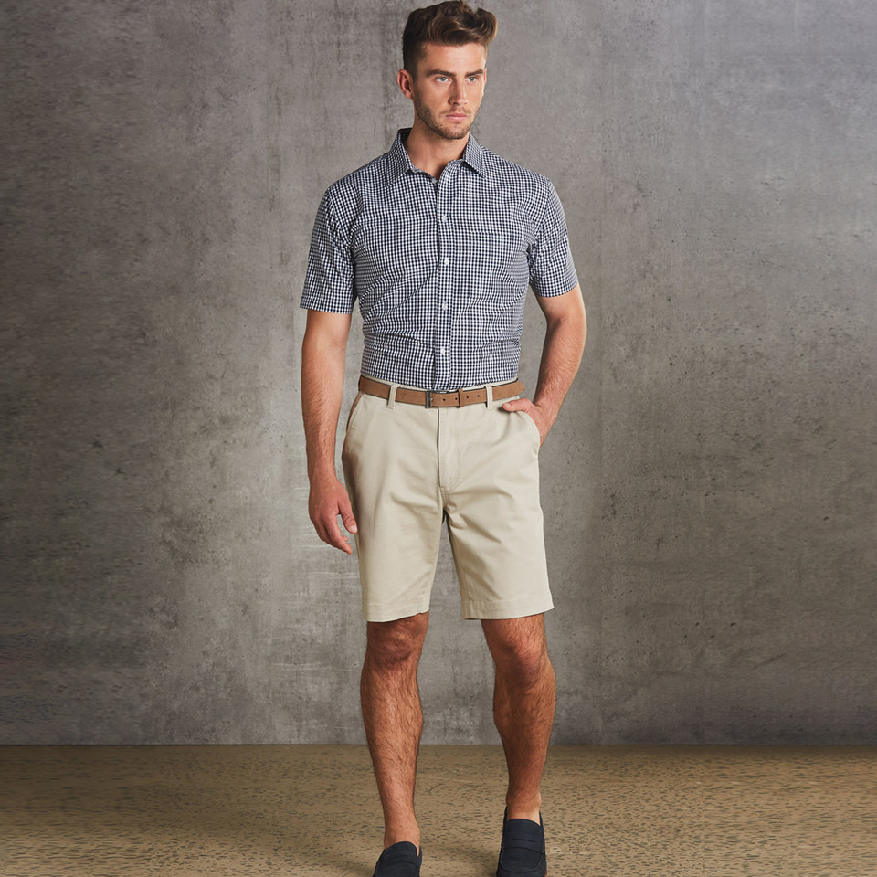 Stone beige cotton chino shorts with front pockets and belt loops, paired with navy gingham check shirt