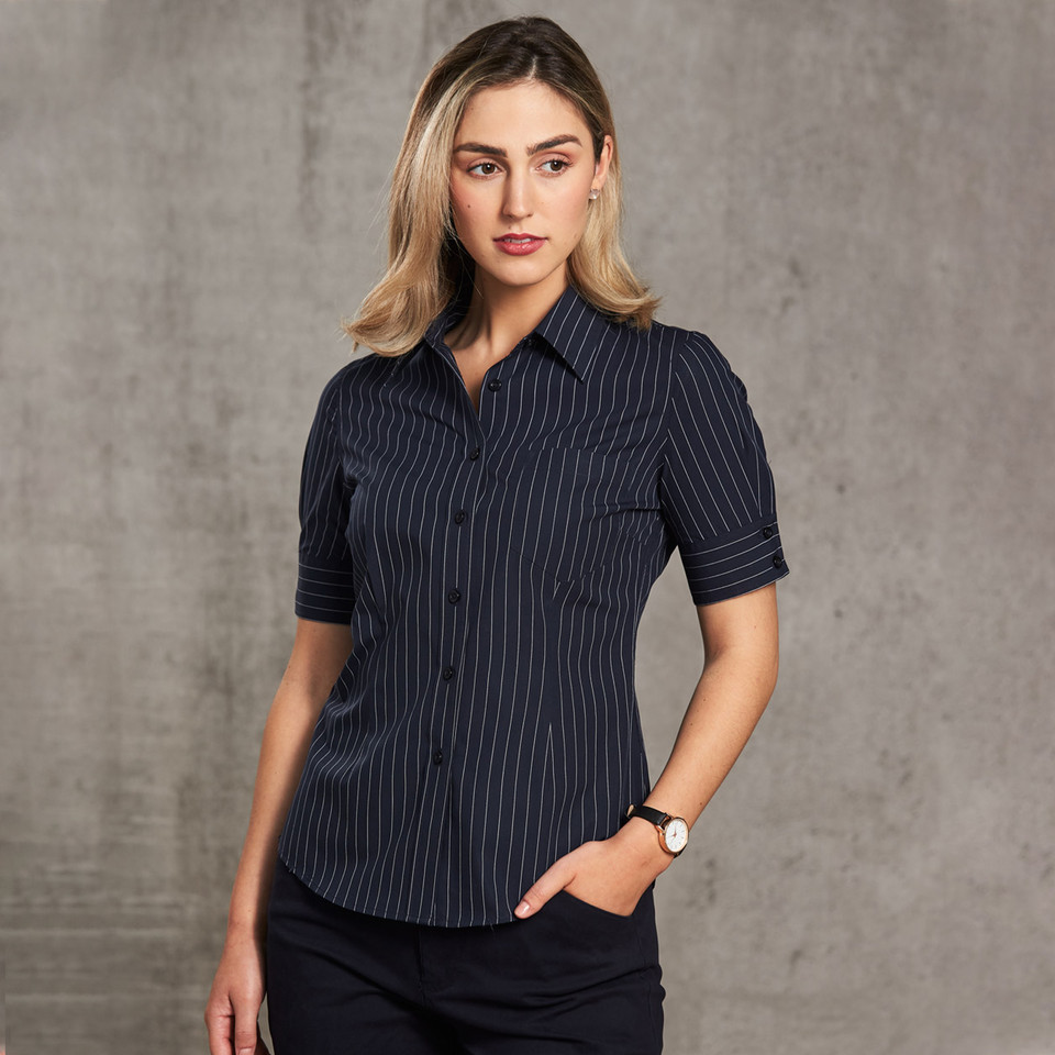 Woman wearing navy pinstripe short sleeve shirt with point collar, chest pocket, and button placket
