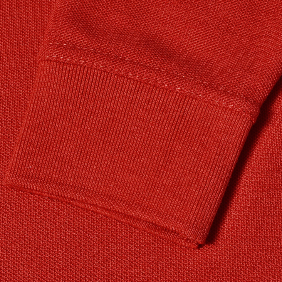 Bright red long sleeve polo shirt showing ribbed cuff and pique knit texture detail