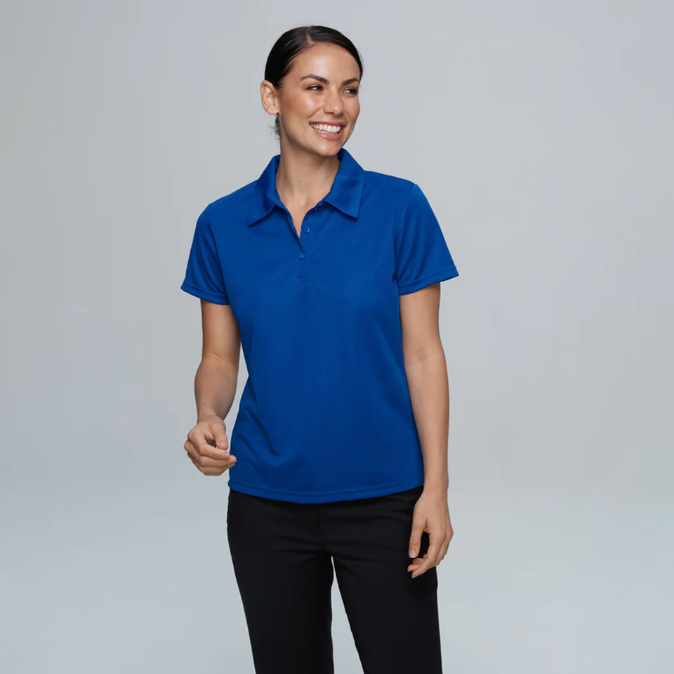 Woman wearing royal blue short-sleeve polo with zip placket and mini waffle texture, styled with black pants