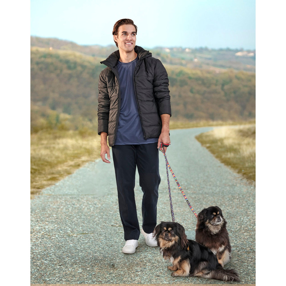 Man walking two dogs outdoors wearing a charcoal quilted puffer jacket with hood and zippered chest pockets