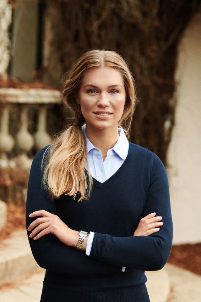 Navy V-neck sweater with light blue collar detail worn over shirt