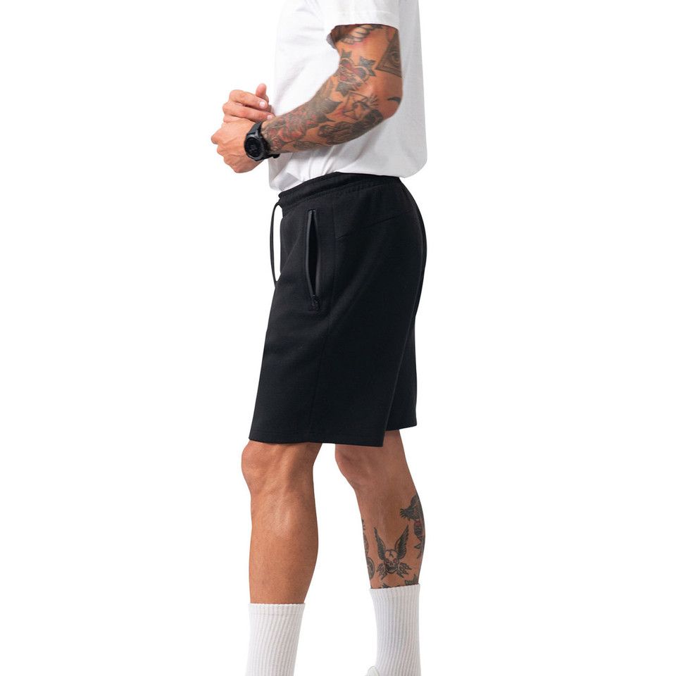 Male model wearing black drawstring shorts with side zip pockets, knee-length cut and clean flat front panel