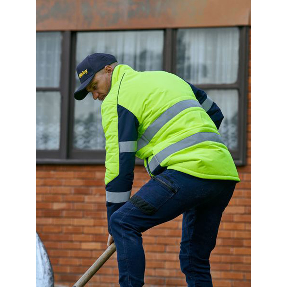 Man shovelling outdoors in fluoro yellow and navy hi vis puffer jacket with reflective tape panels