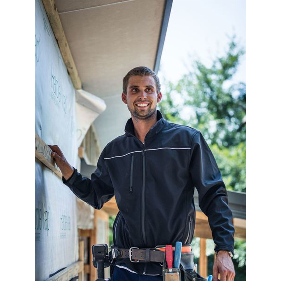 Male tradesperson on building site wearing navy soft shell jacket with reflective piping and full-length zip