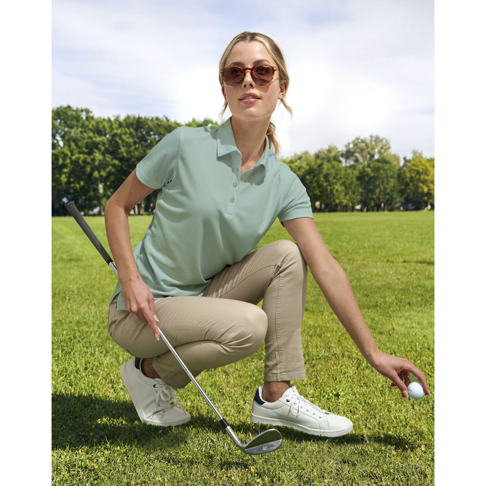 Sage green ladies polo shirt with collar and button placket, paired with beige pants on golf course