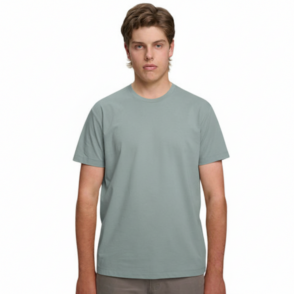 A male model with light brown hair wearing a plain pastel blue Soho Men's Premium New Tech Cotton Face T-shirt, standing against a white background.