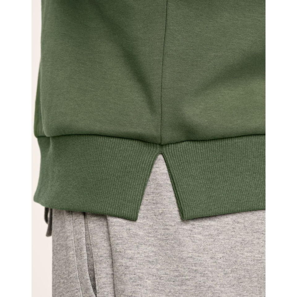 Olive green sweater hem with ribbed cuffs and side split detail over grey sweatpants