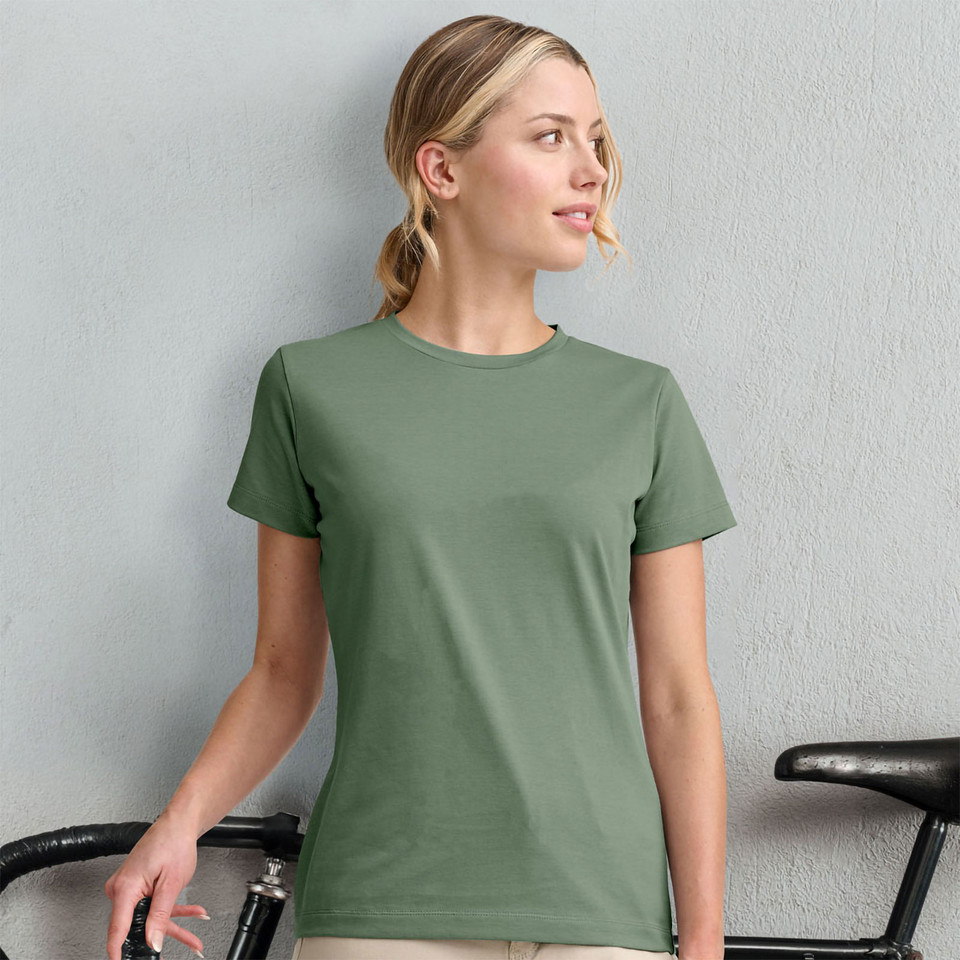 Woman wearing a sage green fitted crew neck short sleeve tee with smooth flat front panel, beside a bicycle