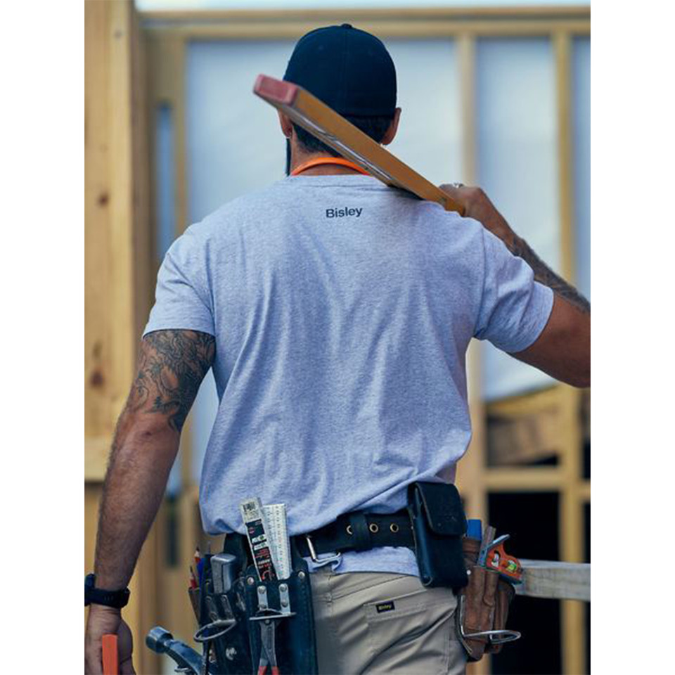 Tradie on construction site wearing light grey marle cotton tee, rear view showing small chest logo print