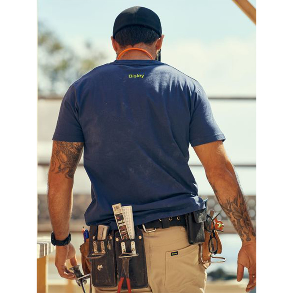 Tradie wearing navy cotton crew neck tee with Bisley logo on upper back, on a worksite