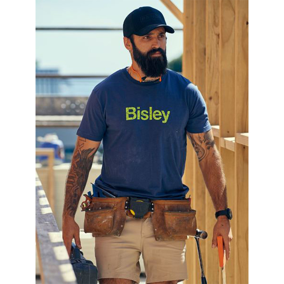 Tradie wearing navy cotton crew neck tee with lime green Bisley chest print on a construction site