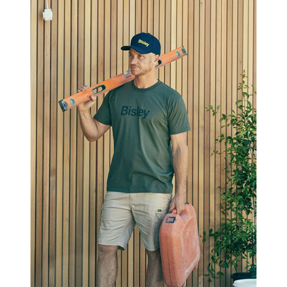 Man wearing olive green cotton crew neck tee with Bisley chest logo print, holding a spirit level