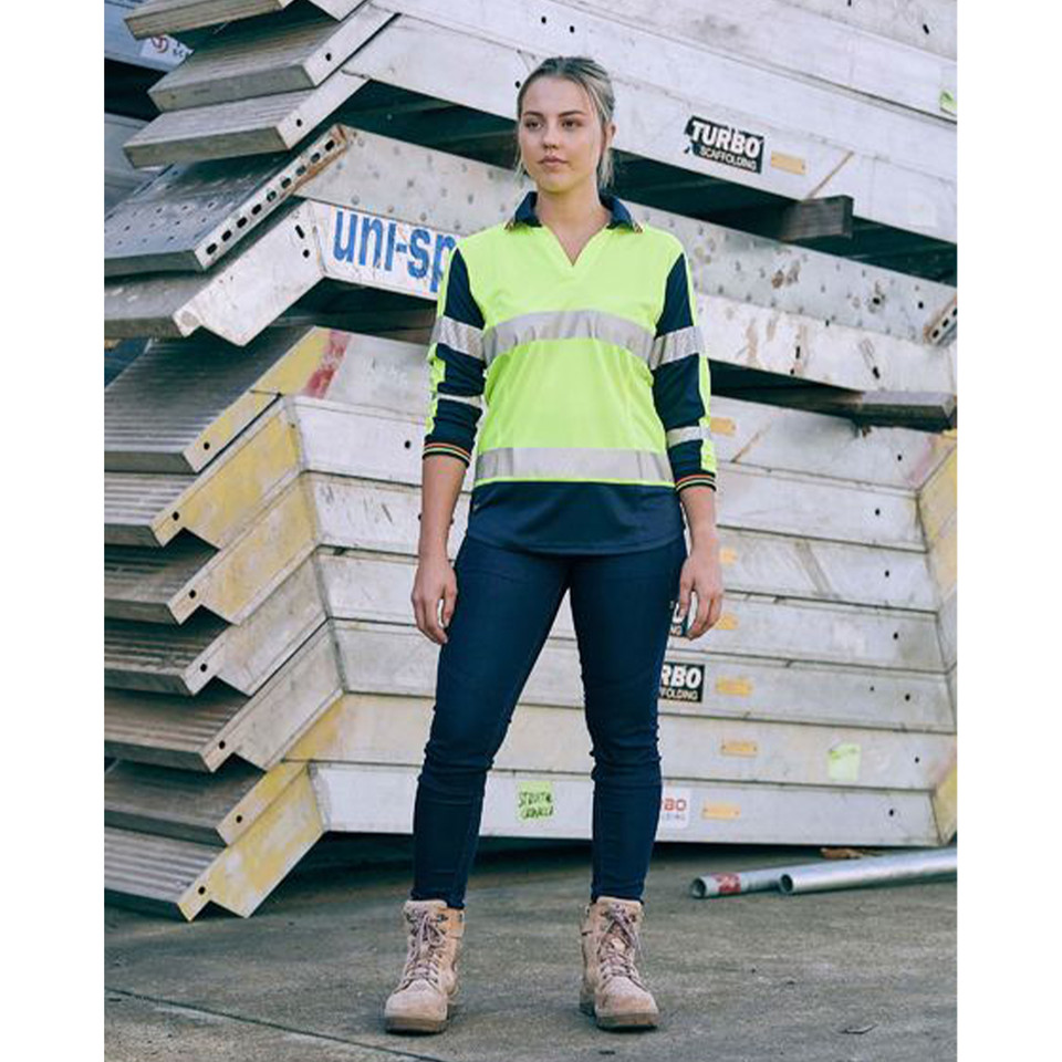 Woman on worksite wearing navy stretch jeggings with hi-vis yellow and navy long sleeve polo
