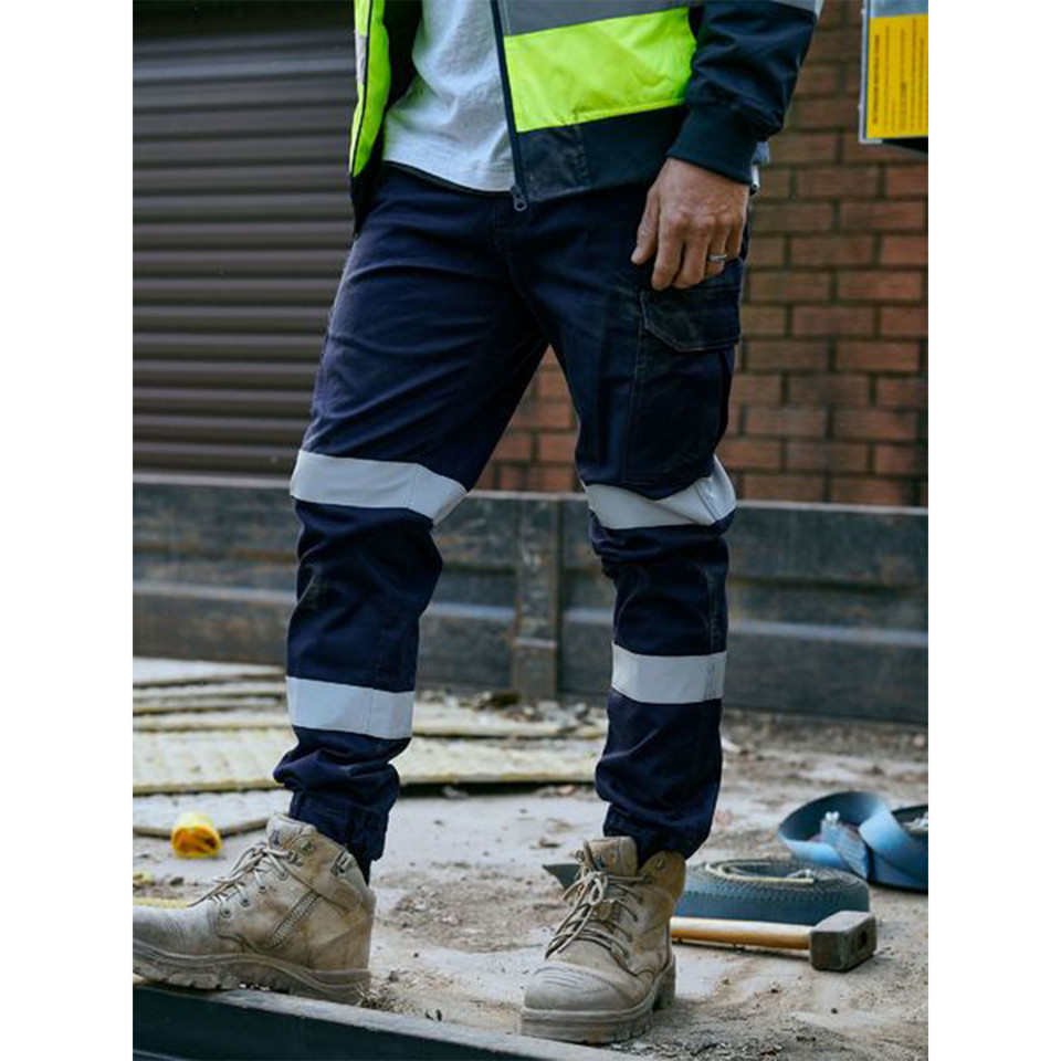 Navy cargo pants with silver reflective tape at knees and cuffed hems on construction site