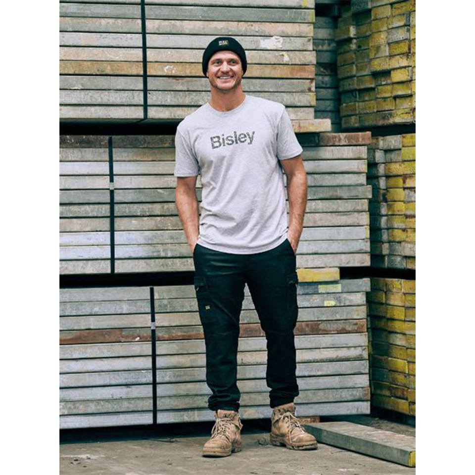 Navy stretch denim cargo pants with cuffed hems and multiple utility pockets worn with white tee and beanie
