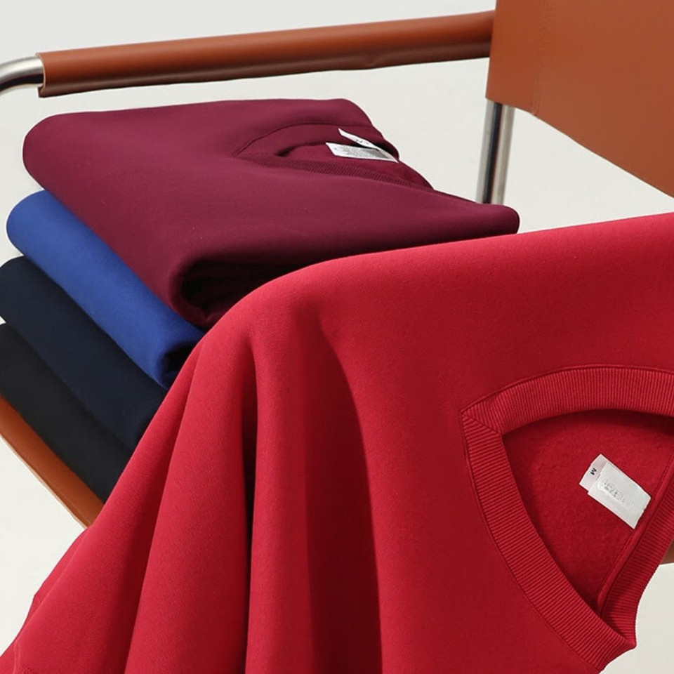 Stack of v-neck fleece sweaters in red, maroon, royal blue and navy showing ribbed neckline detail