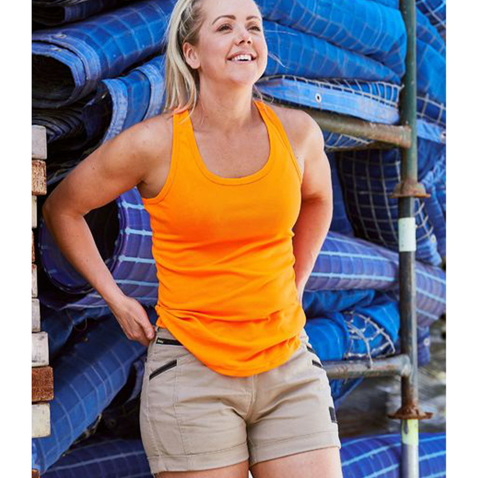 Woman wearing a bright orange racerback singlet and khaki mid-rise shorts in a worksite setting