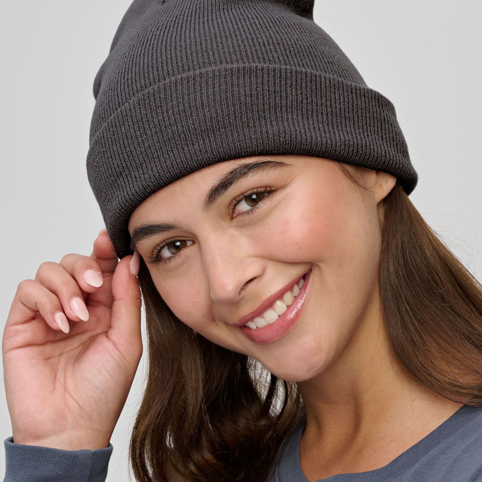 Woman wearing a charcoal ribbed knit beanie with a fold-up cuff, styled casually