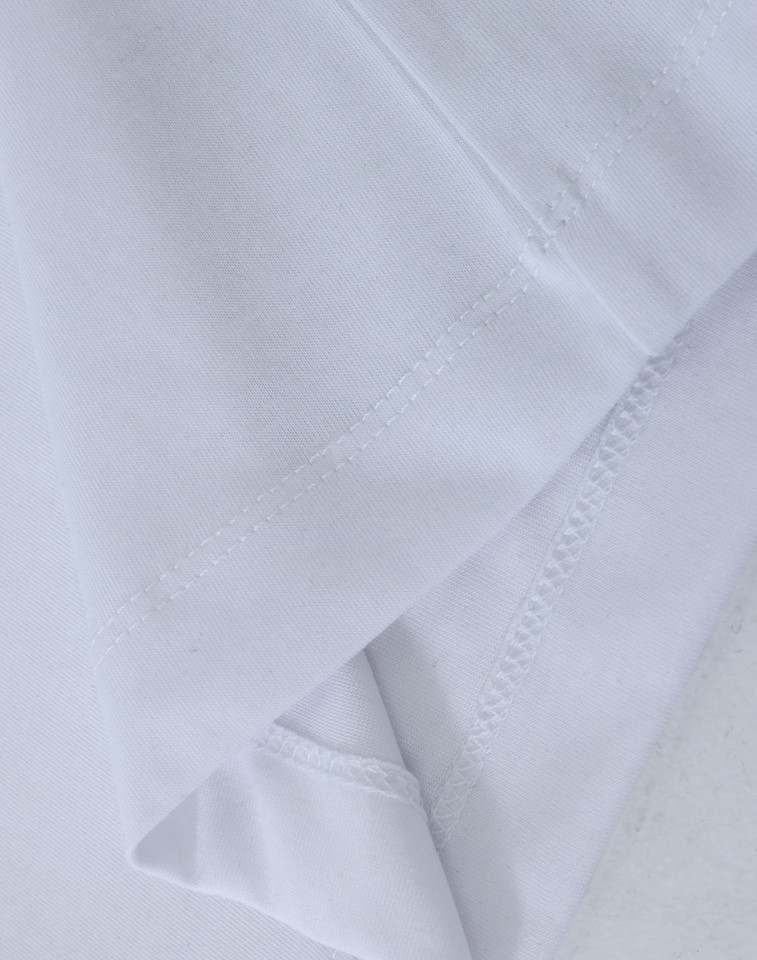 Close-up of white long sleeve tee showing smooth fabric surface and clean flatlock side seam stitching