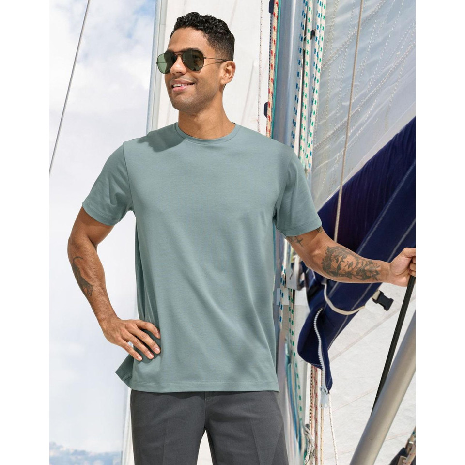 Man wearing a pastel blue premium crew neck tee on a marina deck, smooth fabric with clean seams