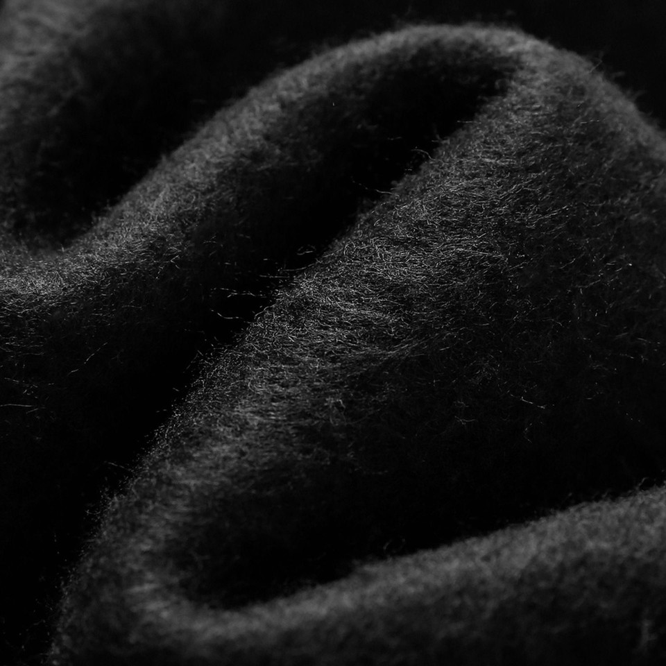 Black oversized hoodie fabric showing soft cotton-rich fleece texture with draped folds