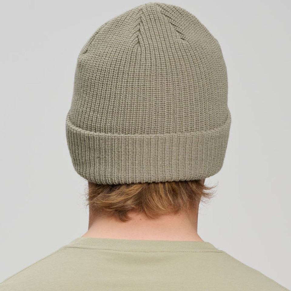 Oatmeal cable knit beanie with rolled cuff shown from back, ribbed texture detail visible