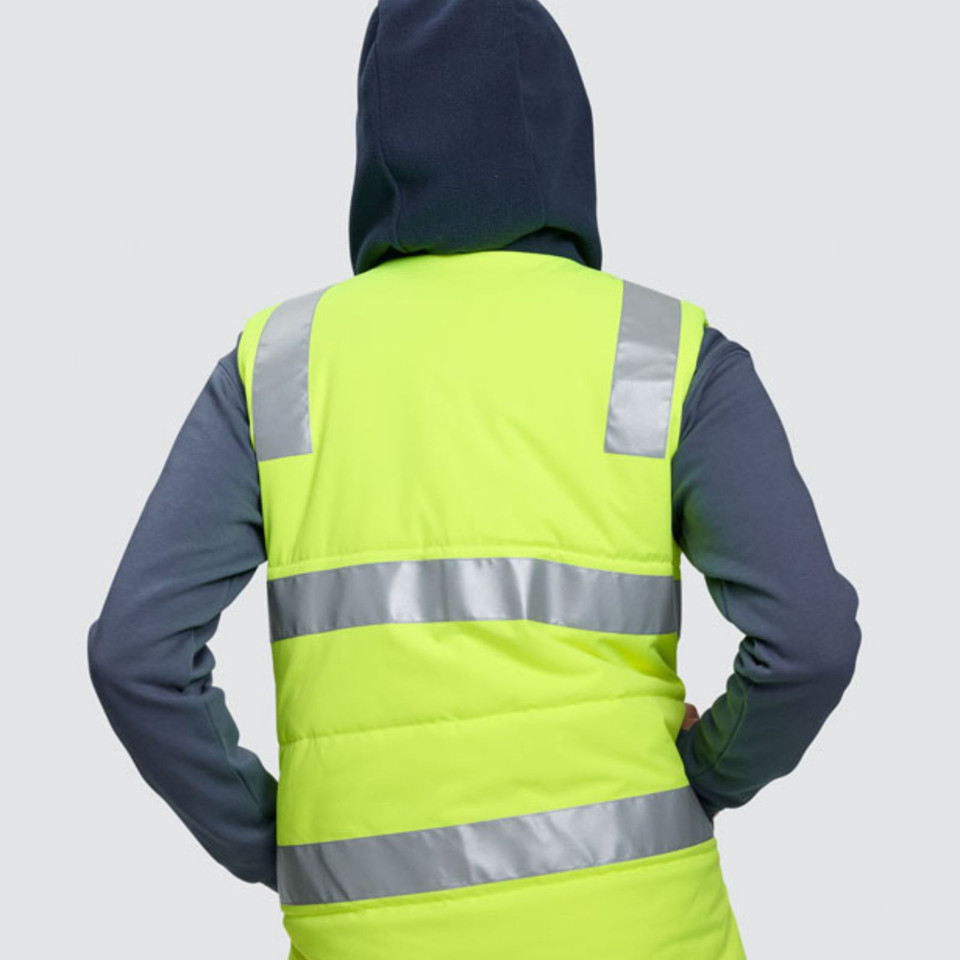 High-visibility yellow vest with reflective silver tape over navy hooded puffer jacket, back view