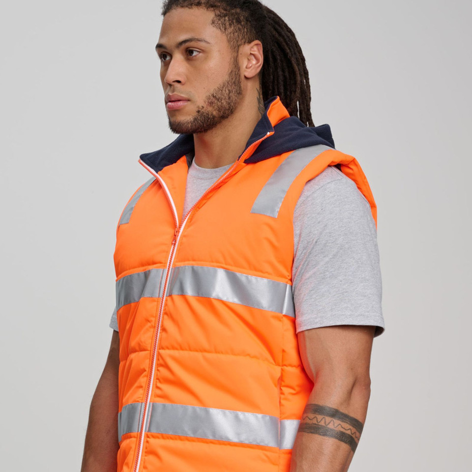 Man wearing fluorescent orange hi-vis puffer vest with navy hood, silver reflective tape across chest and waist, zip front