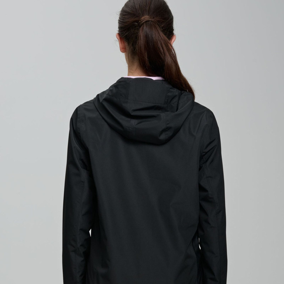 Back view of model wearing a black lightweight hooded jacket with smooth shell fabric and relaxed fit