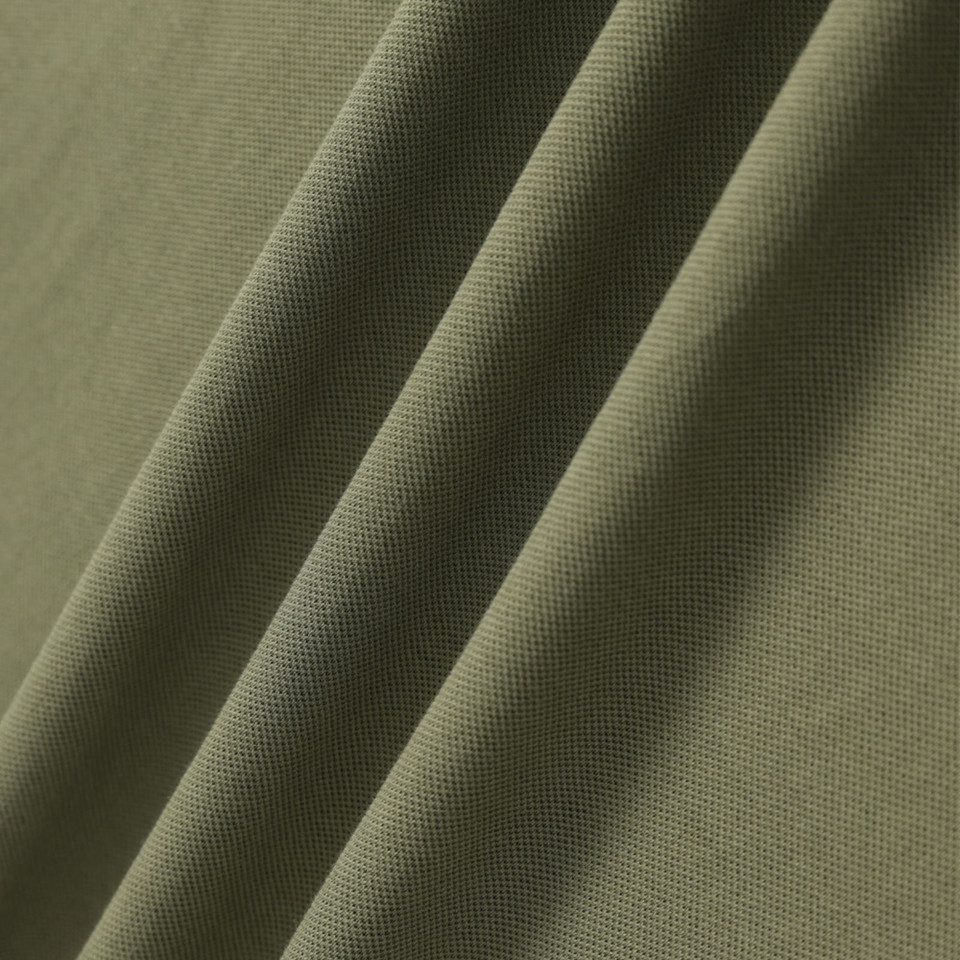 Sage green polo shirt fabric showing fine pique textured knit with soft diagonal folds