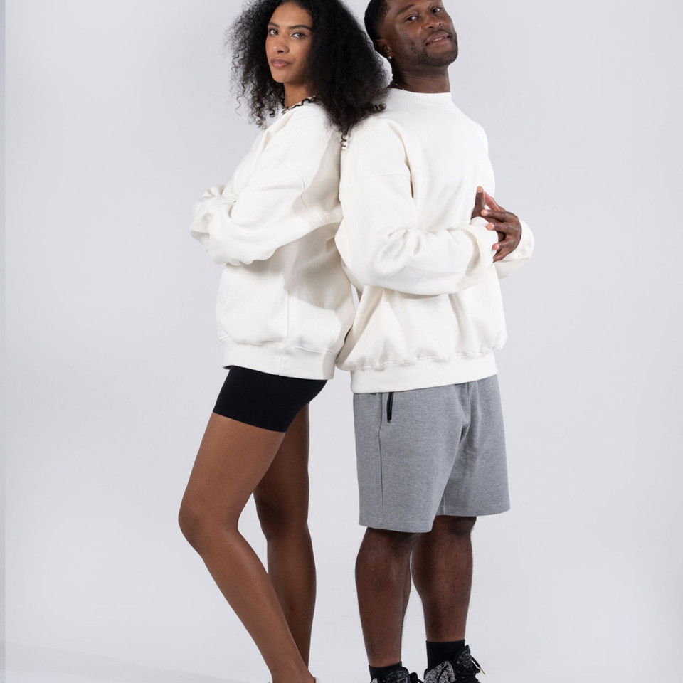 Unisex oversized cream crew neck sweatshirts with dropped shoulders and ribbed cuffs modelled with black and grey shorts
