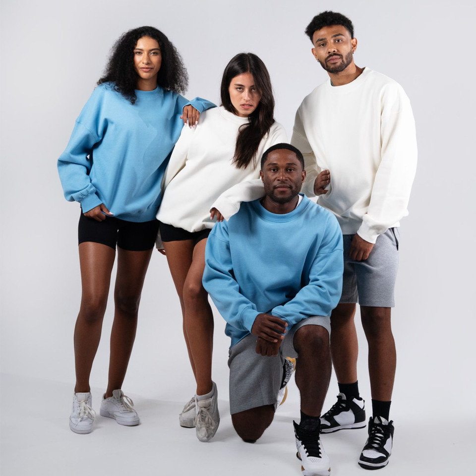 Group wearing oversized crew neck sweaters in Carolina blue and natural white with relaxed dropped shoulders