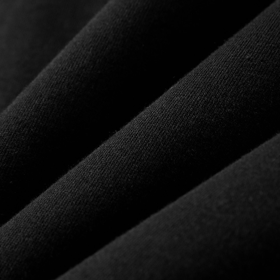 Close-up of black fabric showing fine knit texture with soft diagonal folds and matte finish