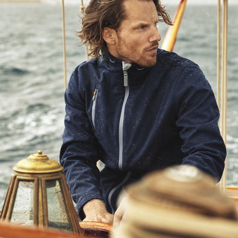 Man on sailboat wearing navy speckle-texture softshell jacket with contrast grey zip and chest pocket