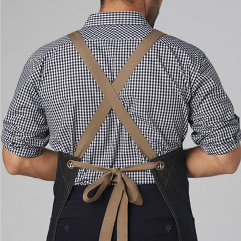 Tan cross-back apron straps with tie closure over navy and white gingham checked shirt
