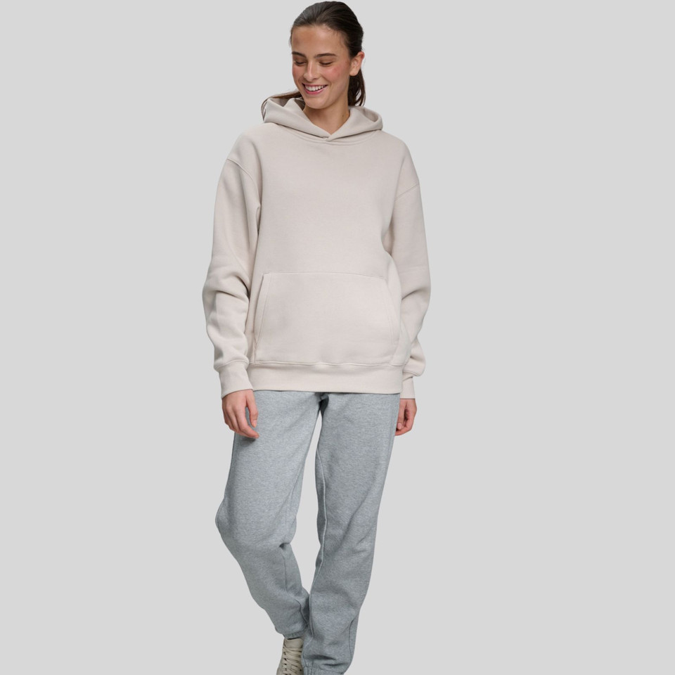 Model wearing an oversized cream pullover hoodie with front kangaroo pocket and ribbed cuffs