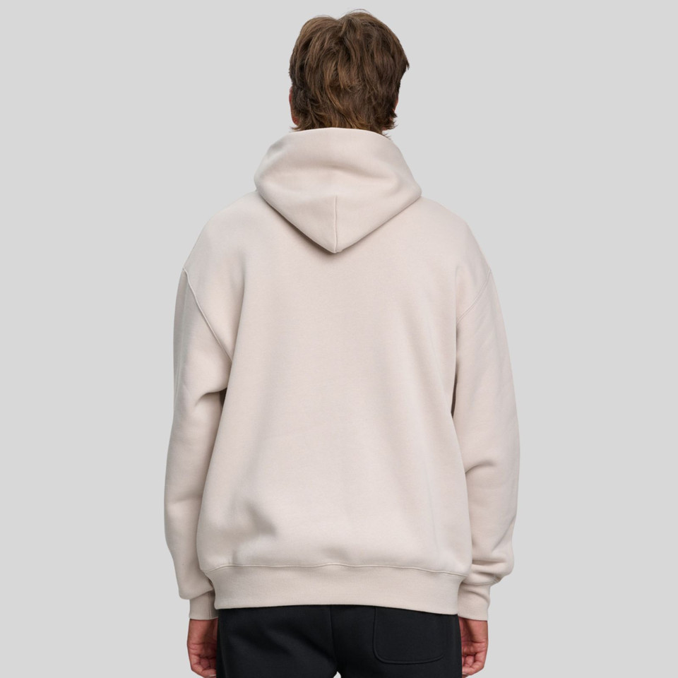 Back view of model wearing an oversized sand pullover hoodie with ribbed hem and large hood