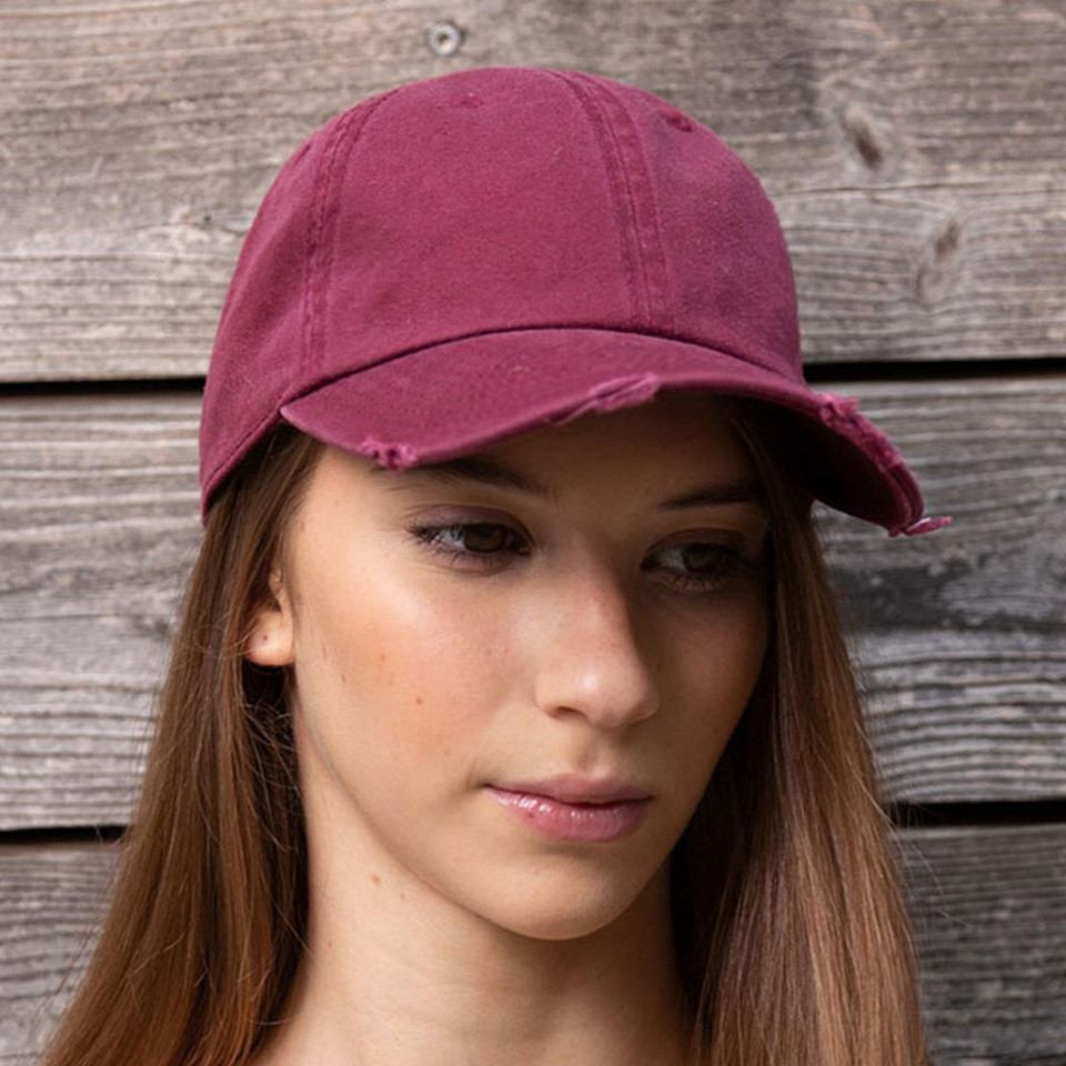 Model wearing a burgundy distressed cotton dad cap with frayed brim edge and washed vintage finish