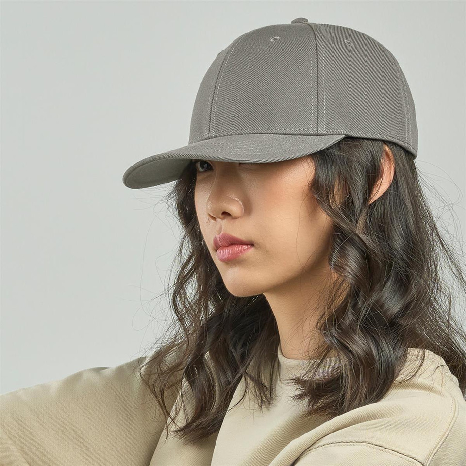 Model wearing a stone grey structured baseball cap with smooth front panel and curved brim