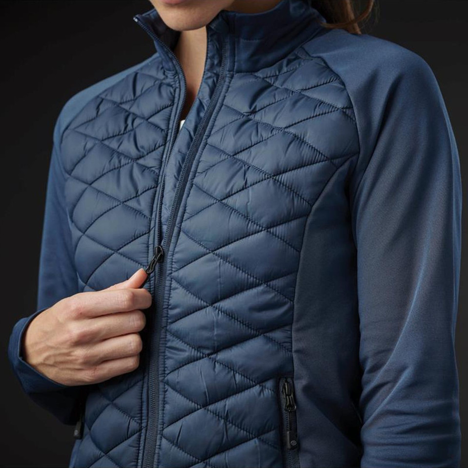 Woman wearing navy blue hybrid jacket with diamond-quilted insulated front panels and smooth stretch fleece sleeves