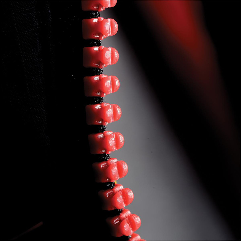 Close-up of red and black contrast zip teeth on a lightweight men's thermal puffer jacket
