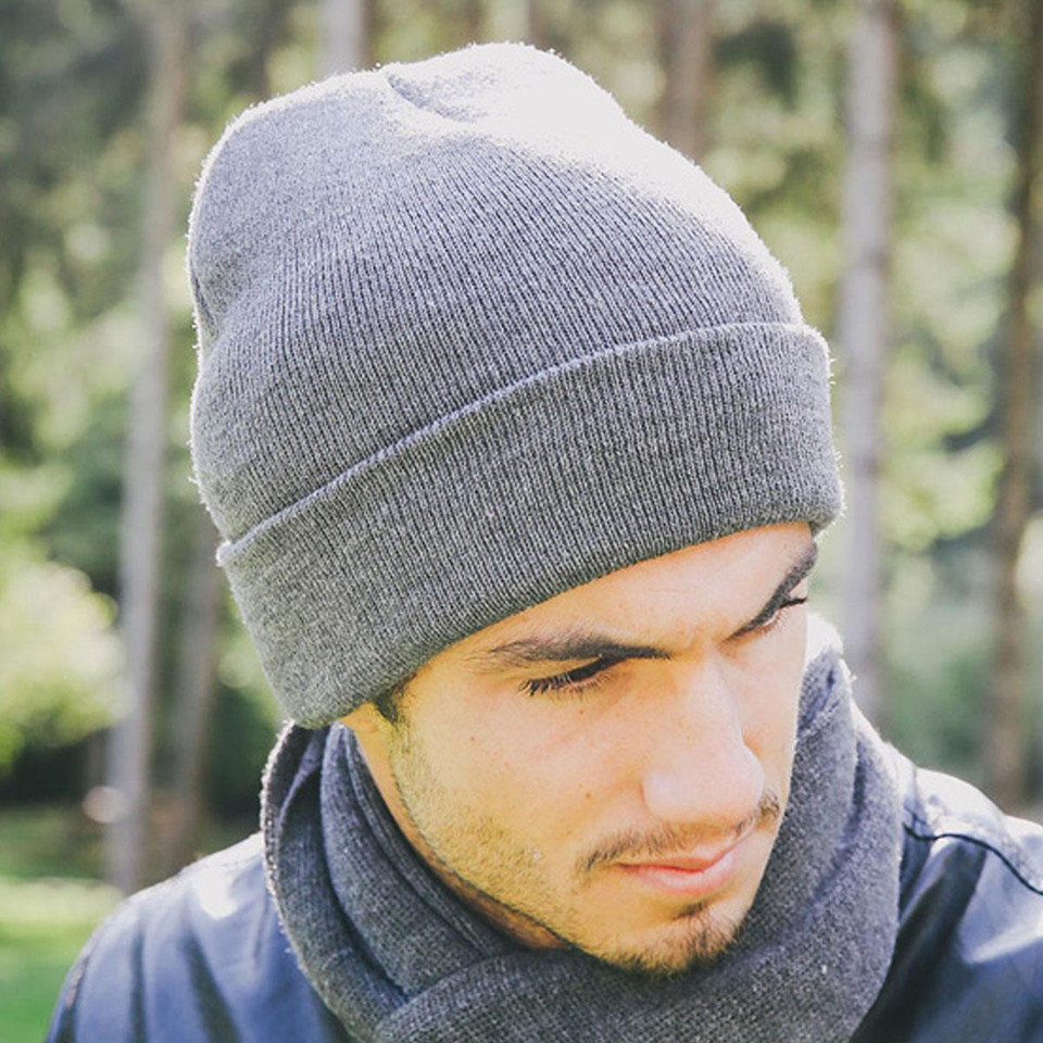 Man wearing a mid-grey ribbed knit cuffed beanie outdoors, wide fold-up cuff with clean flat panel