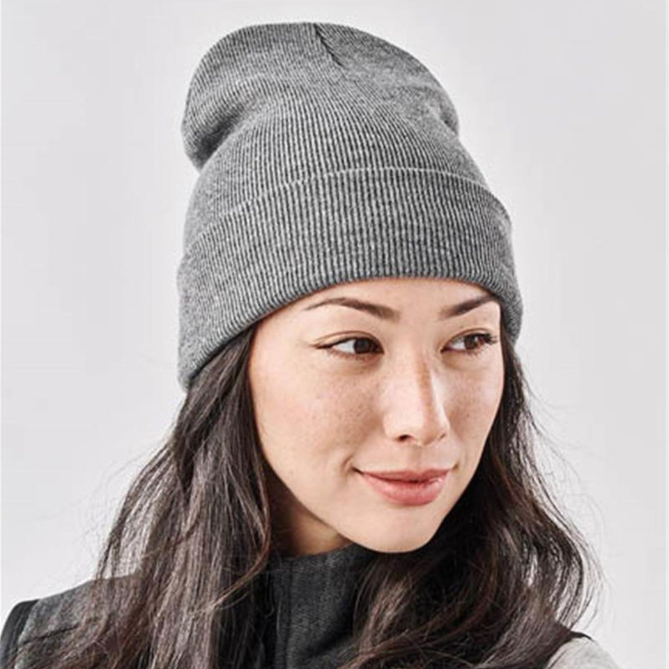 Woman wearing a heather grey fine-rib knit beanie with a classic roll cuff