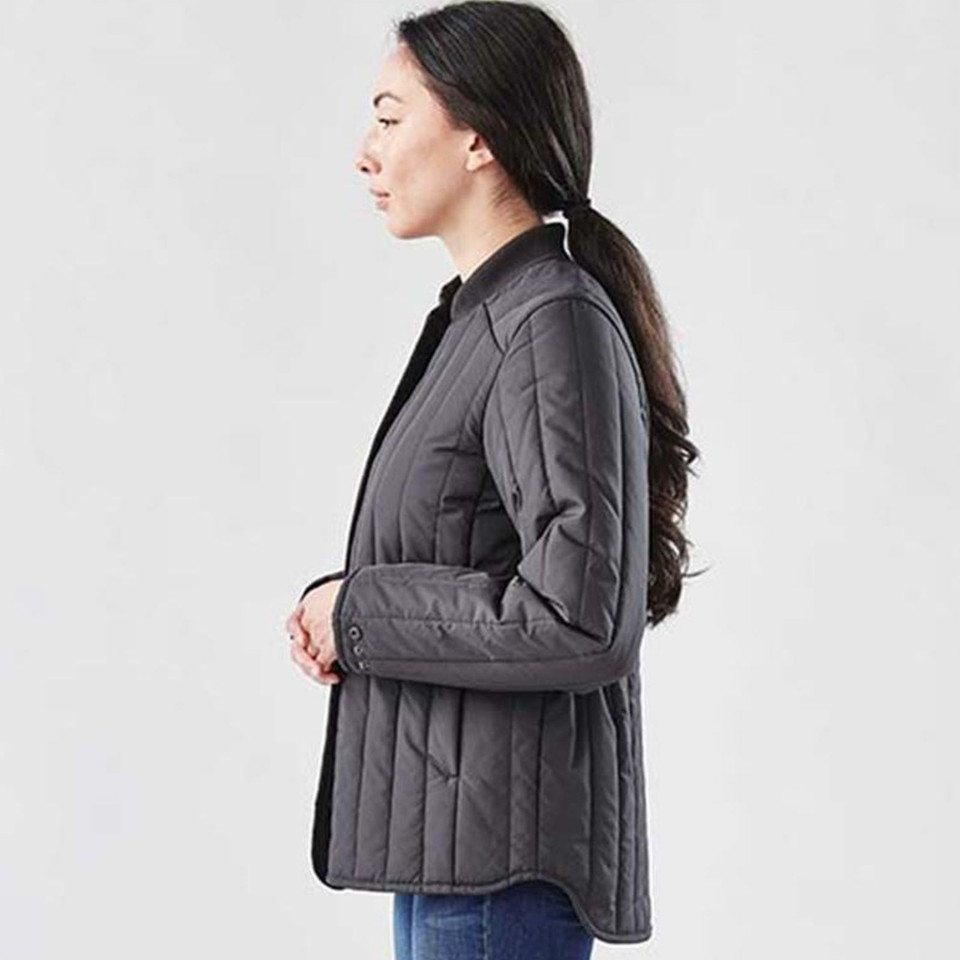 Woman wearing charcoal quilted thermal jacket with snap-adjustable waist, side profile view